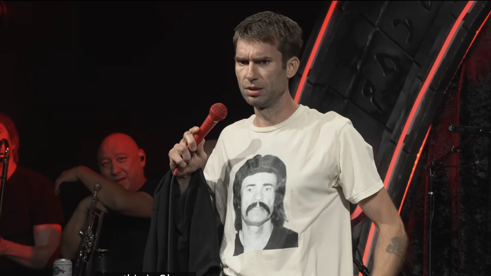 Shane Camp onstage holding a microphone during his Kill Tony performance